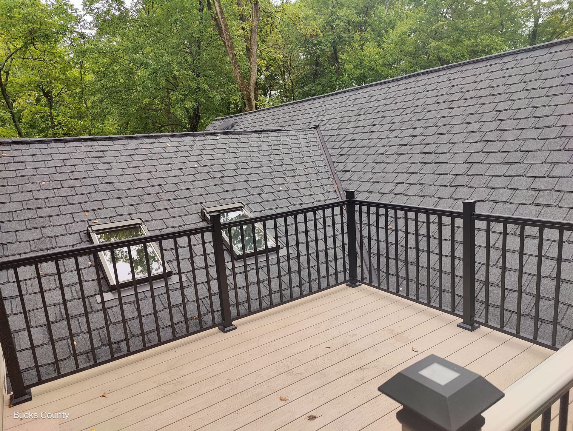 A deck with a railing and a roof in the background.