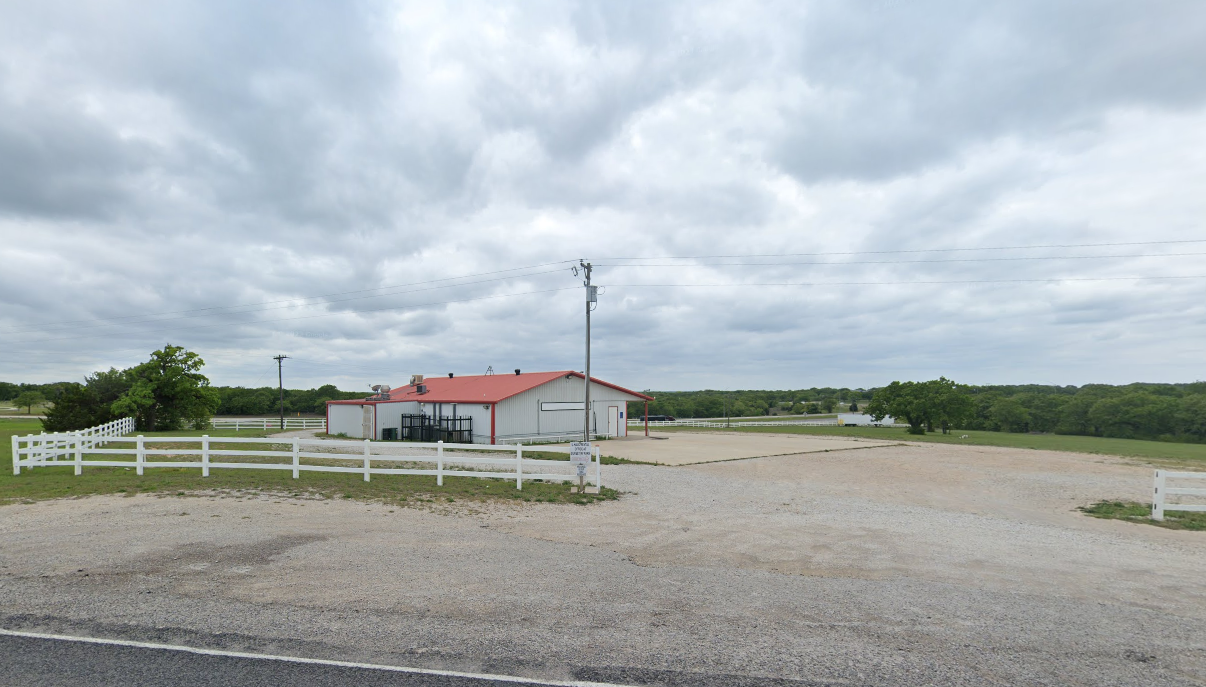 a white fence surrounds a house on a cloudy day .