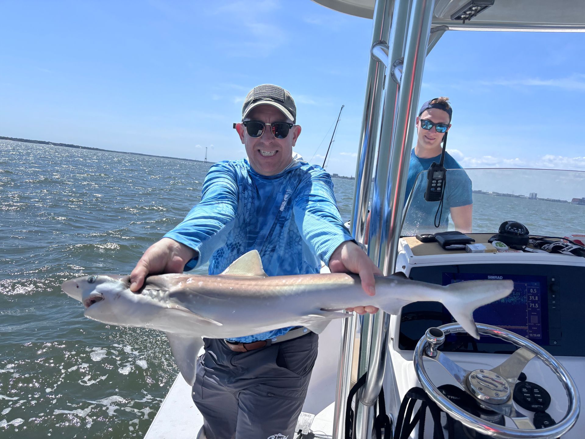 A man is holding a large fish on a boat.