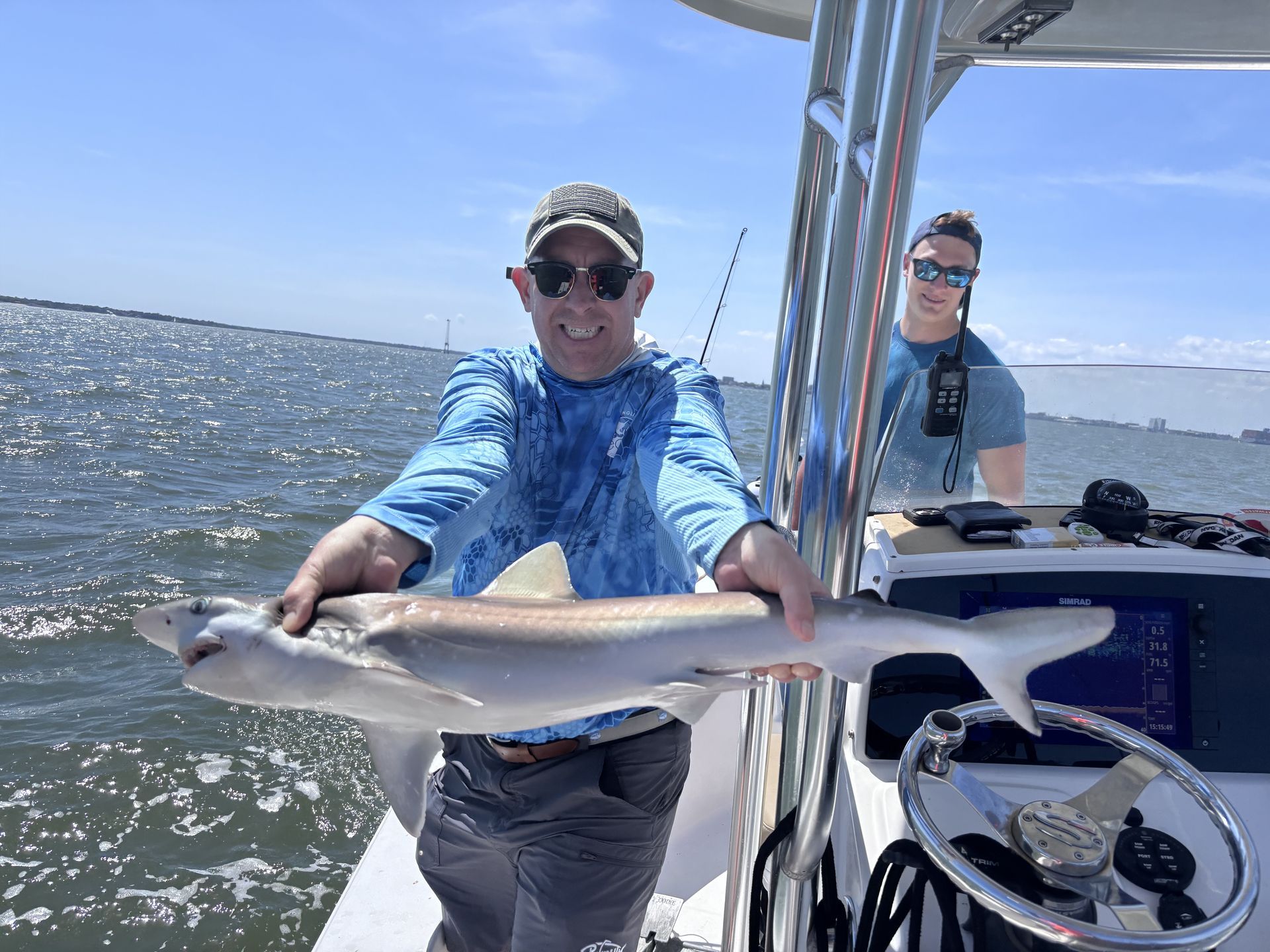 A man is holding a large fish on a boat.