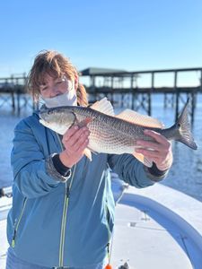 A woman is holding a large fish on a boat.