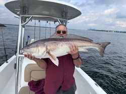 A man is holding a large redfish on a boat.