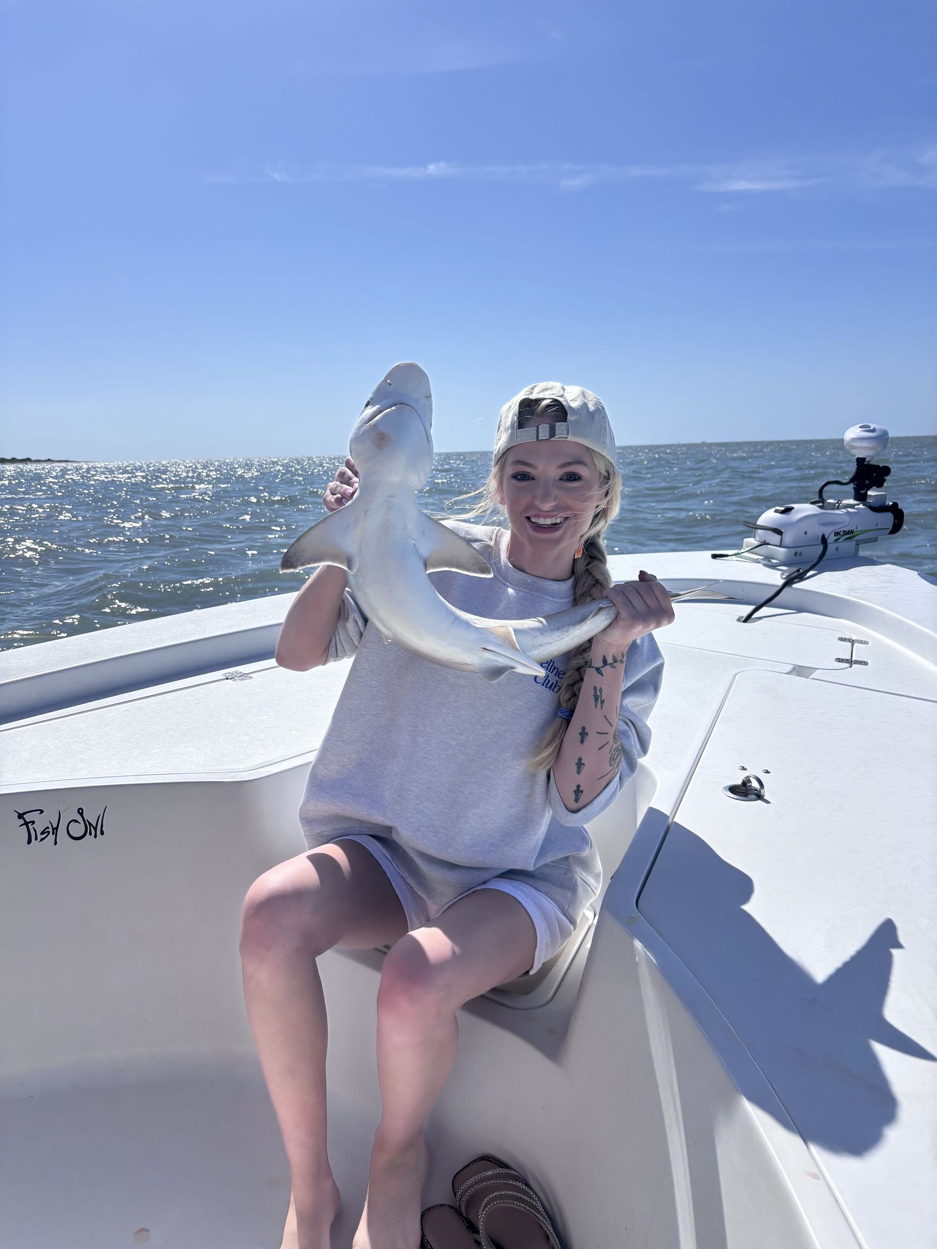 A young girl is sitting on a boat holding a shark.