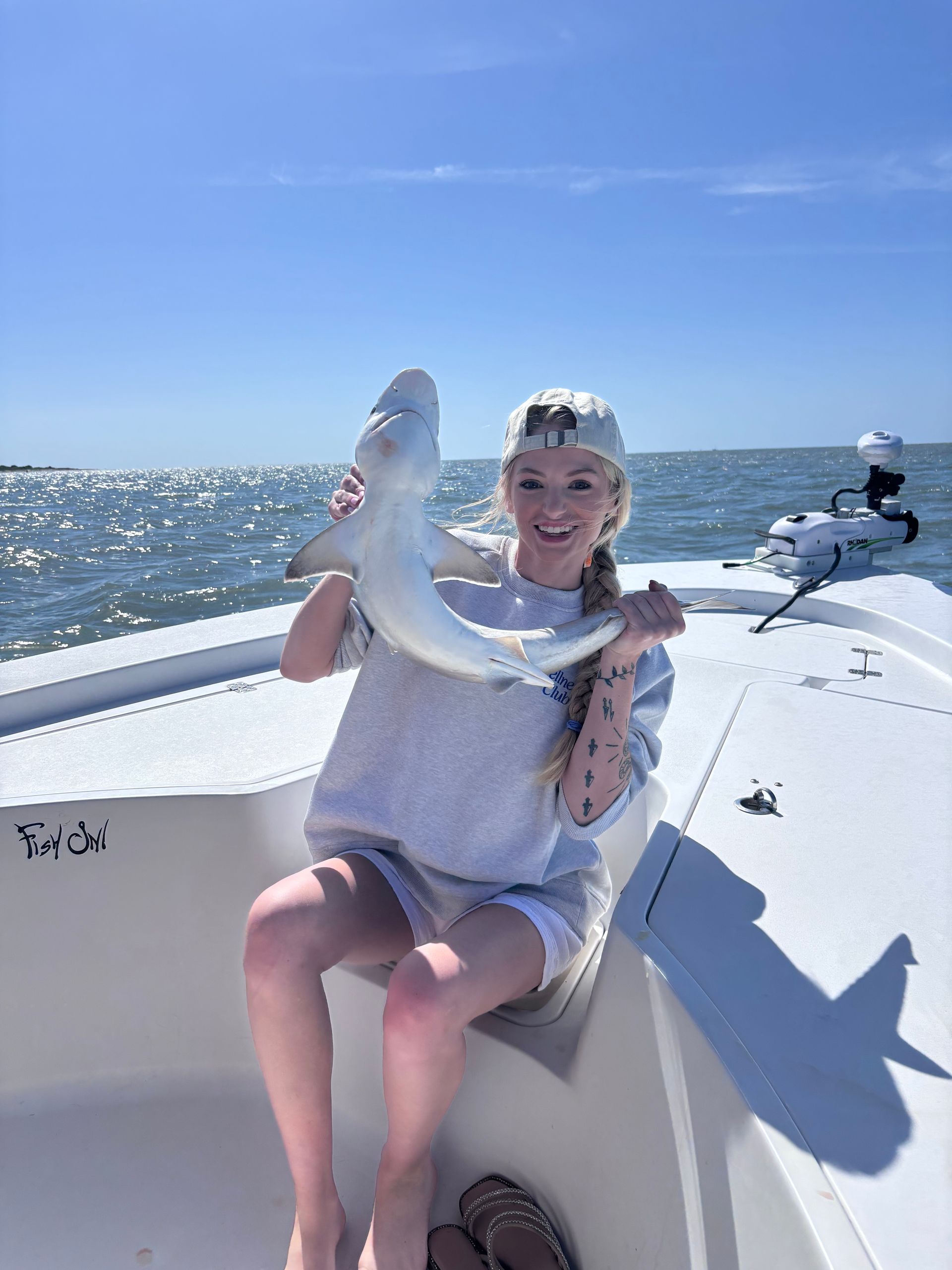 A young girl is sitting on a boat holding a shark.