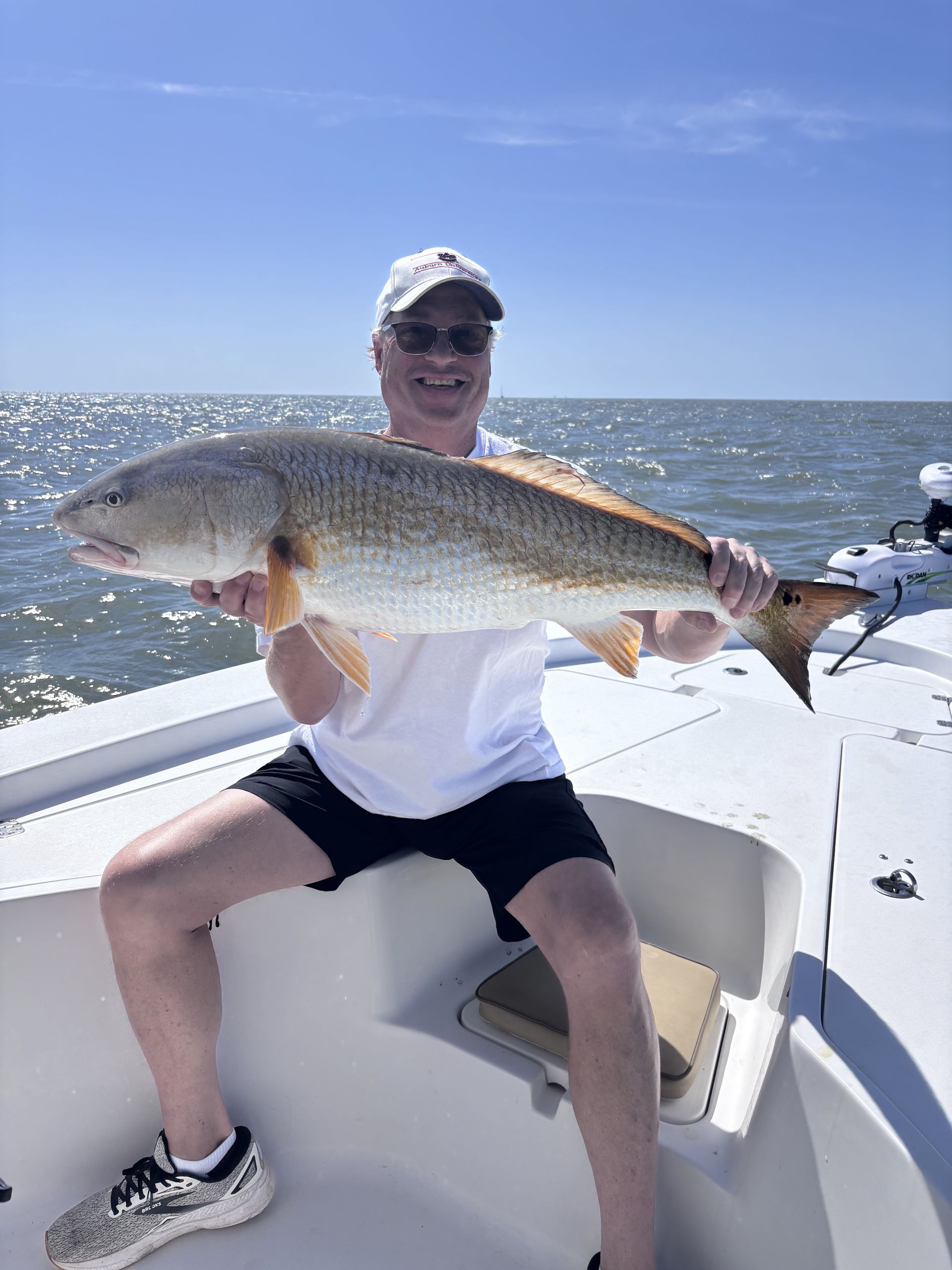 A man is sitting on a boat holding a large fish.