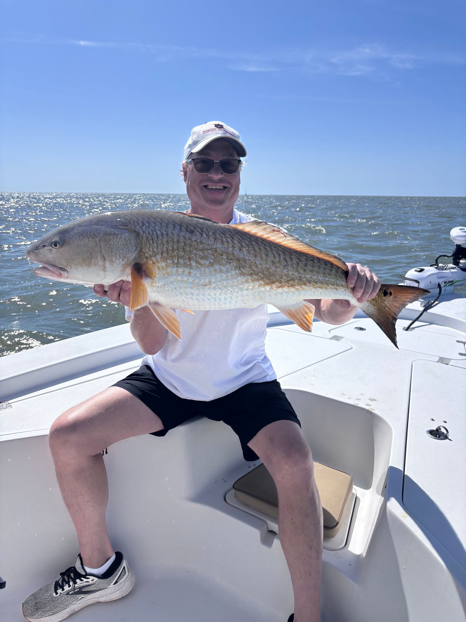 A man is sitting on a boat holding a large fish.