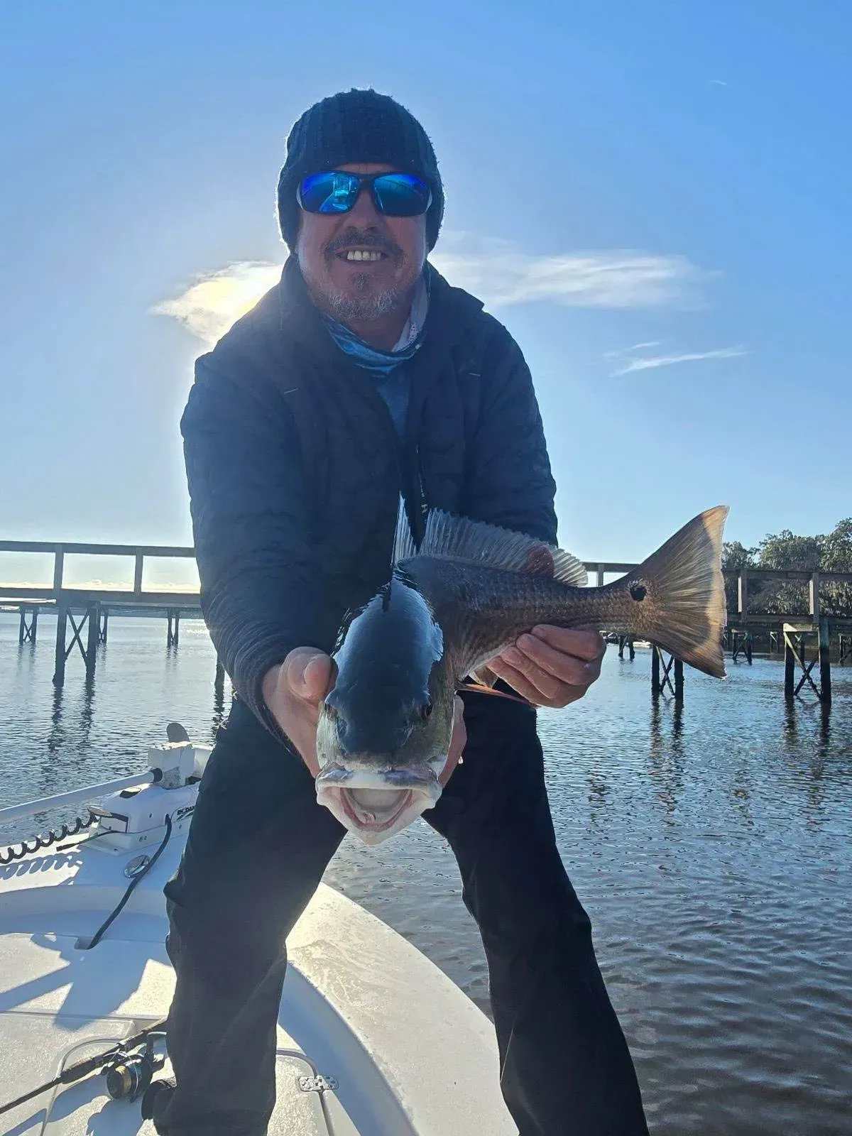 A man is standing on a boat holding a fish in his hands.