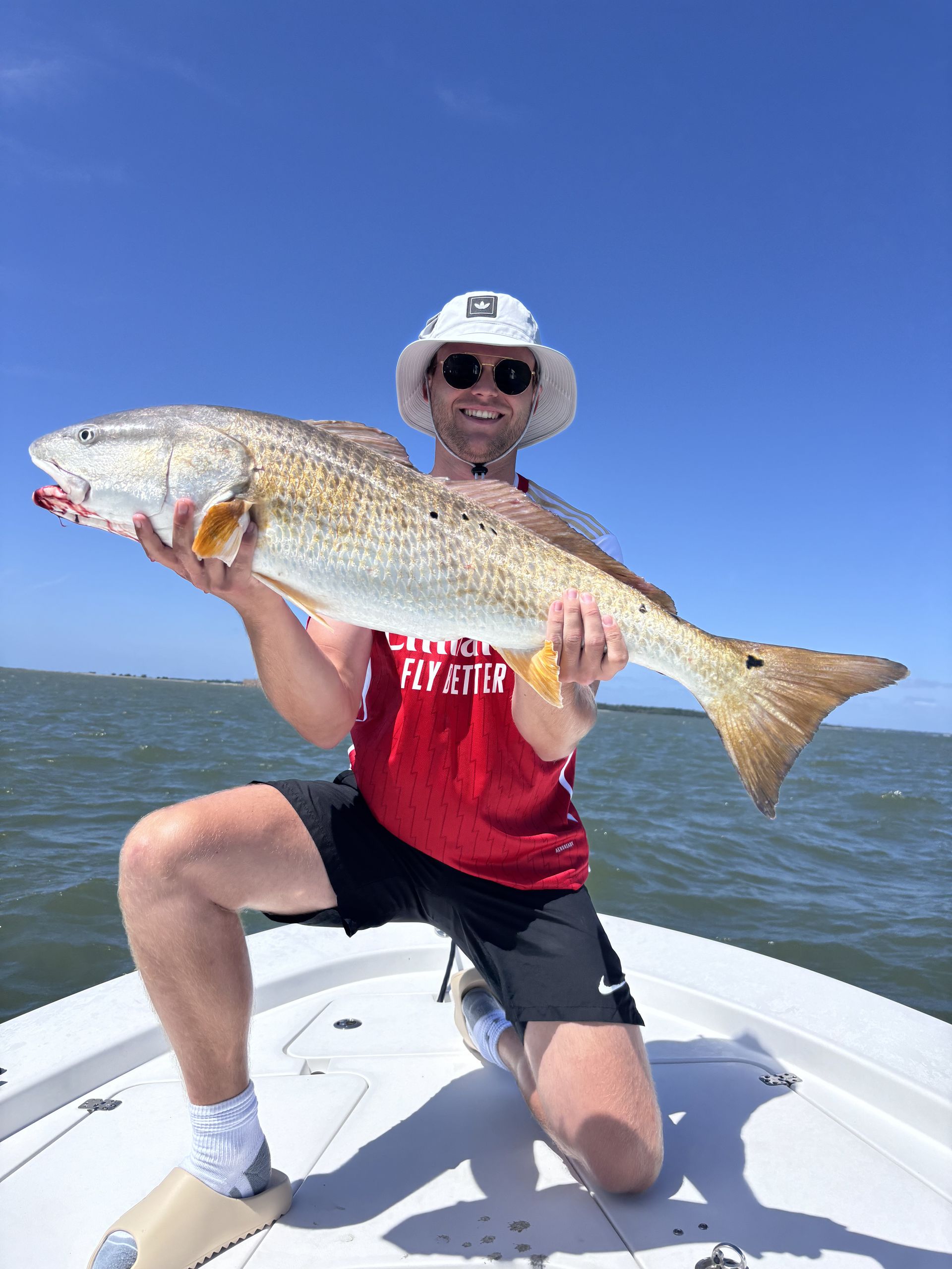 A man is kneeling on a boat holding a large fish.