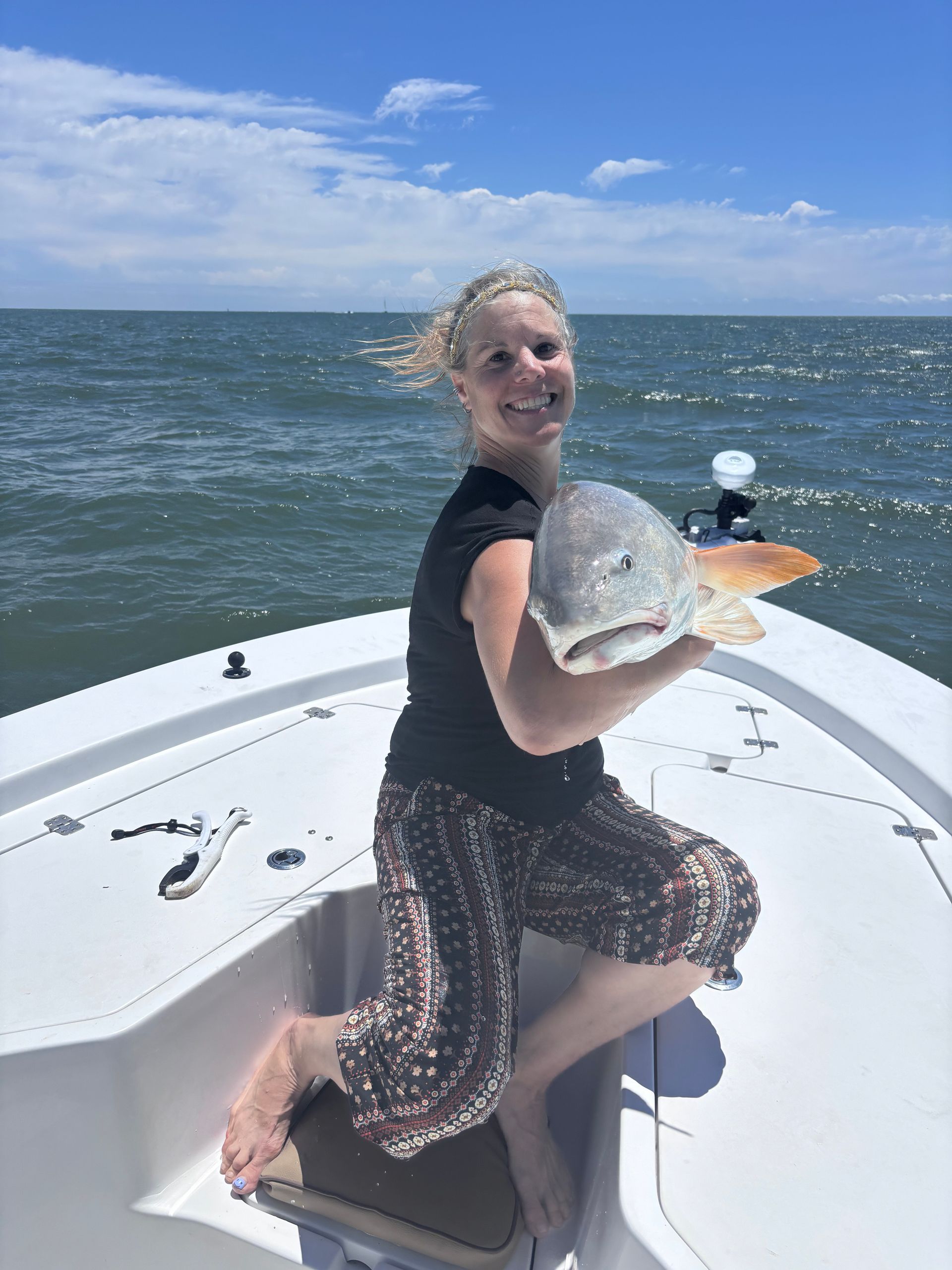 A woman is sitting on a boat holding a large fish.