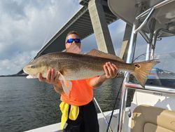 A man is holding a large redfish on a boat.