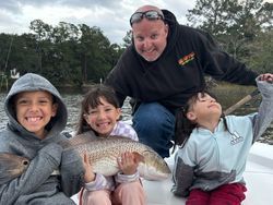 A man and three children are sitting on a boat holding a fish.