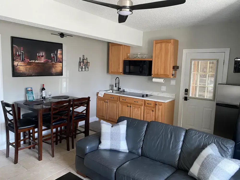A living room with a couch , table and chairs and a kitchen.