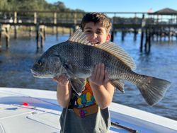 A young boy is holding a large fish on a boat.