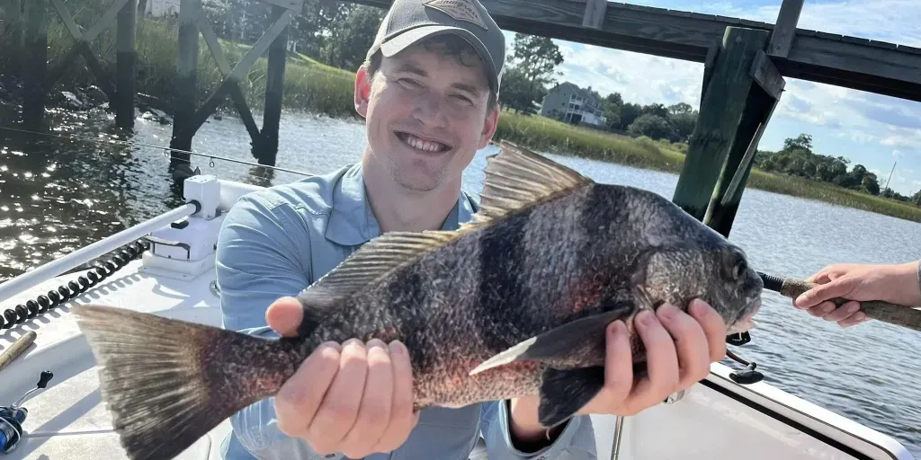 A man is holding a large fish in his hands on a boat.