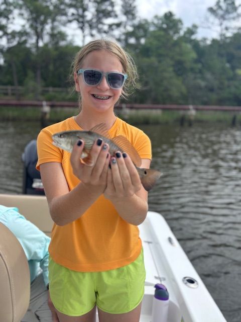 A young girl is holding a fish in her hands on a boat.