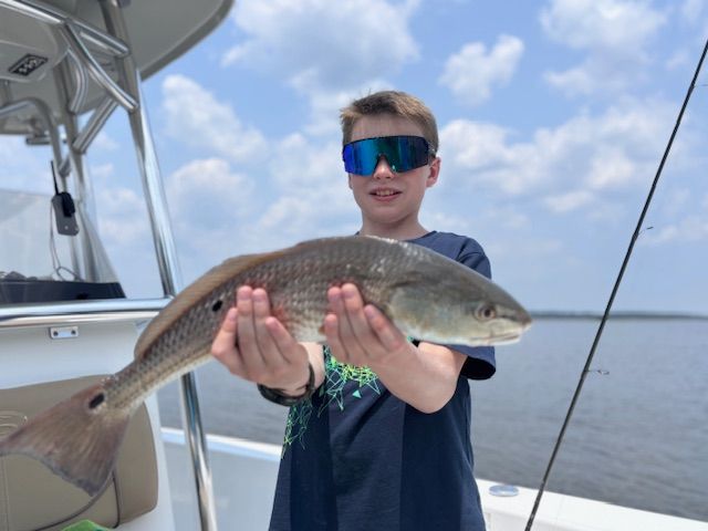 A young boy is holding a large fish on a boat