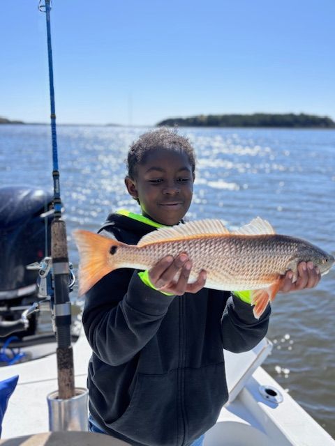 A young boy is holding a fish on a boat