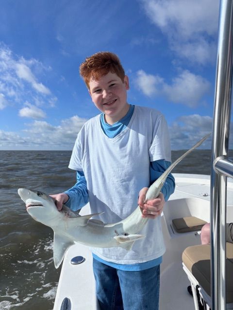 A young boy is holding a shark on a boat.