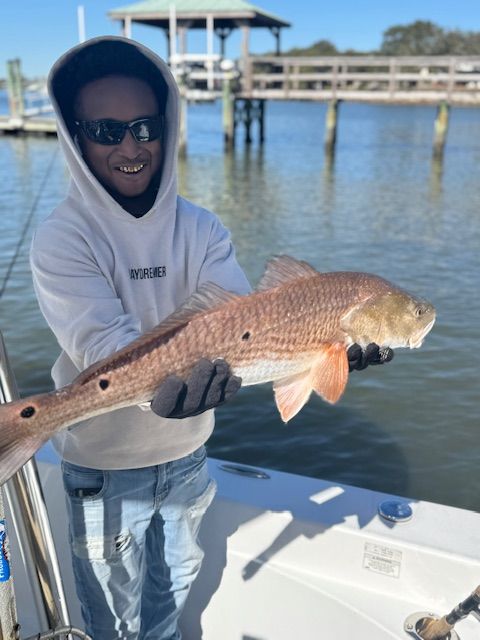 A man is holding a large red fish on a boat.