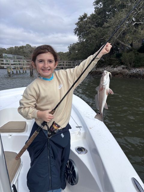 A young boy on a boat holding a fishing rod and a fish