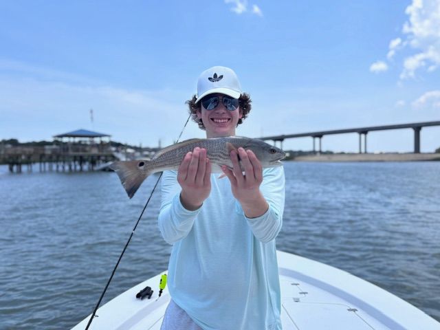 A man on a boat is holding a fish in his hands.