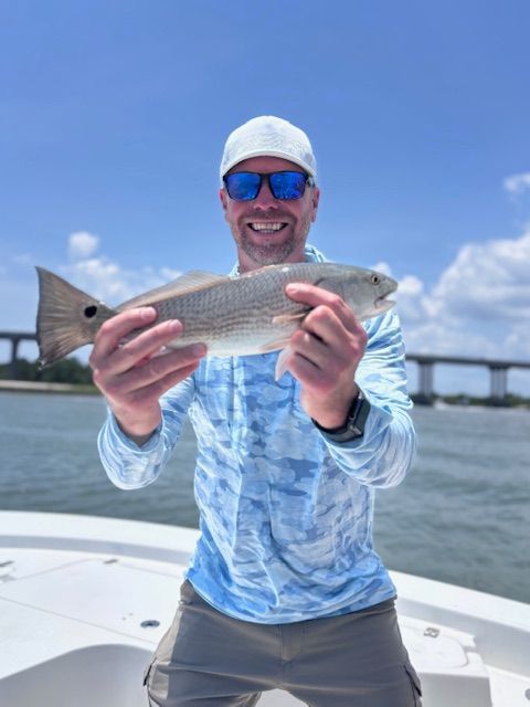 A man is holding a fish in his hands on a boat.
