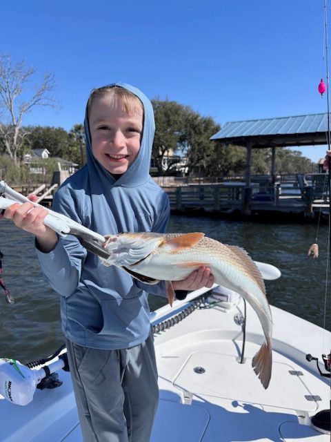 A young boy is holding a large fish on a boat.