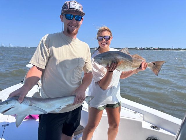 A man and a woman are holding a large fish on a boat.