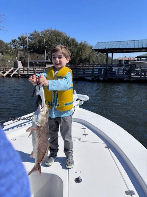 A young boy is holding a large fish on a boat