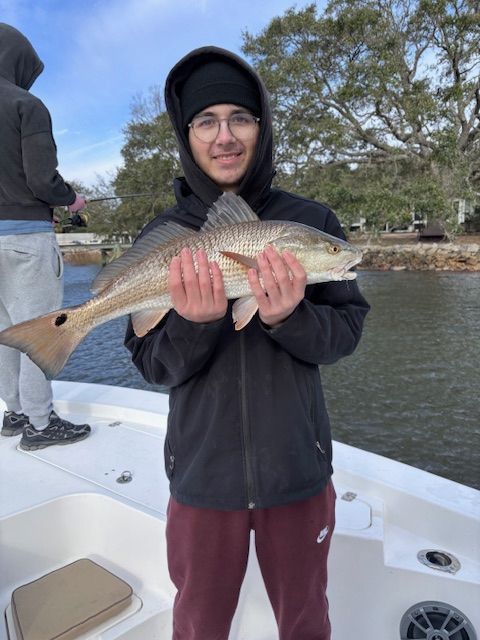A young man is holding a large fish on a boat