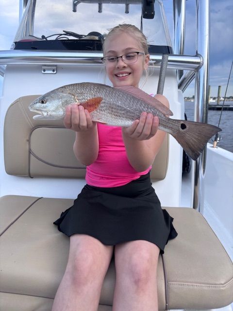 A young girl is sitting on a boat holding a large fish