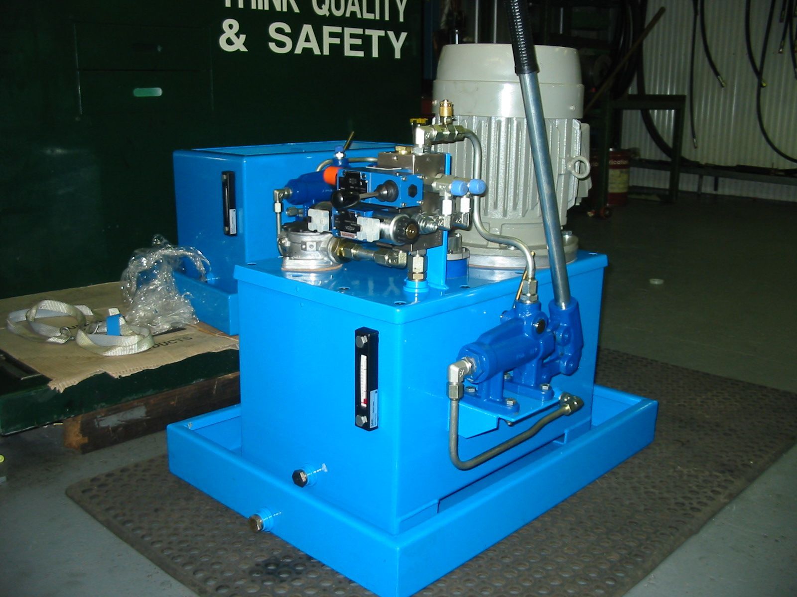 A blue machine is sitting in front of a sign that says think quality & safety