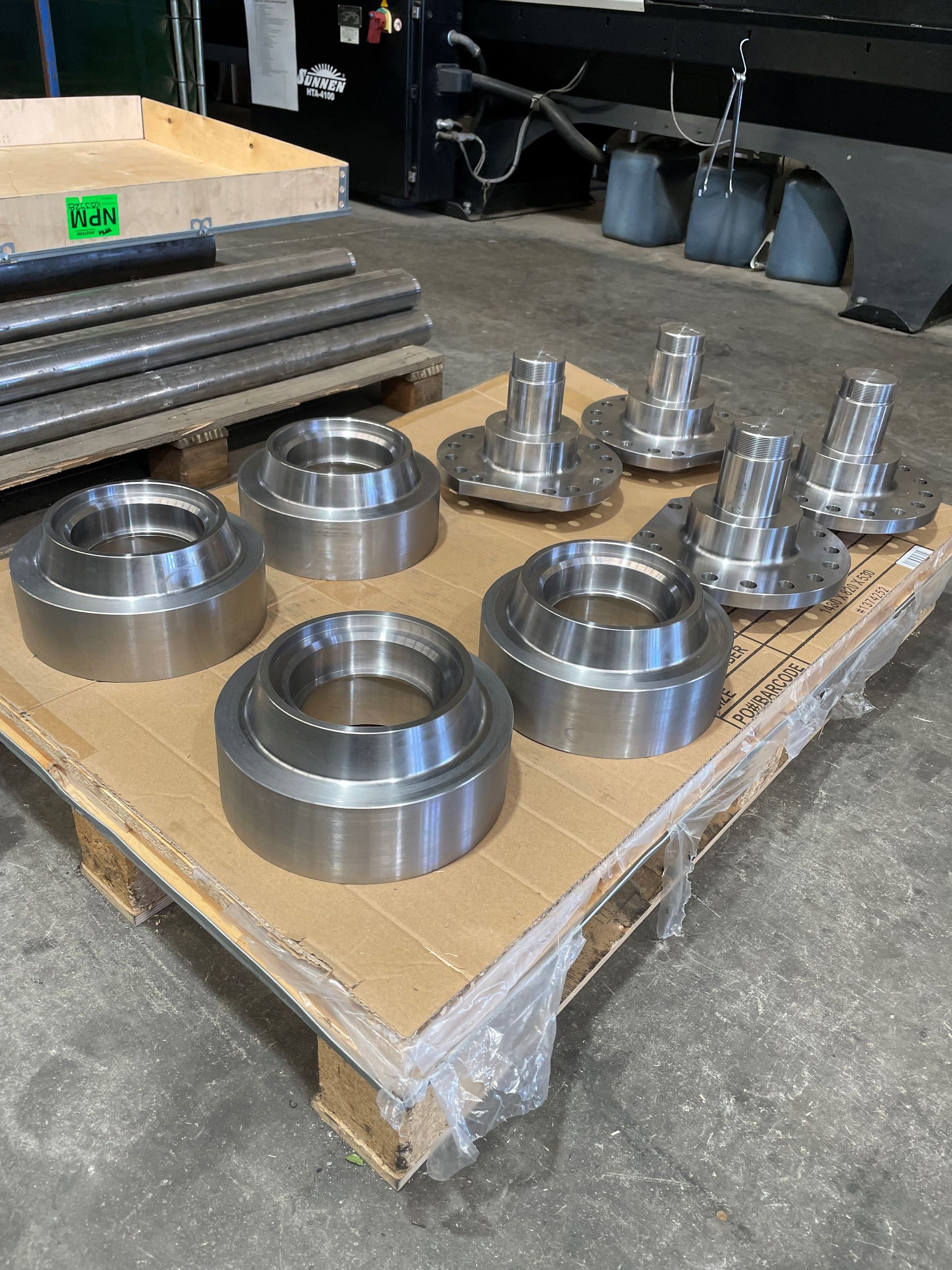 A pallet of metal parts is sitting on a concrete floor.