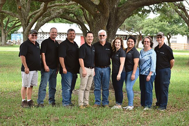 A group of people are posing for a picture in front of a tree.
