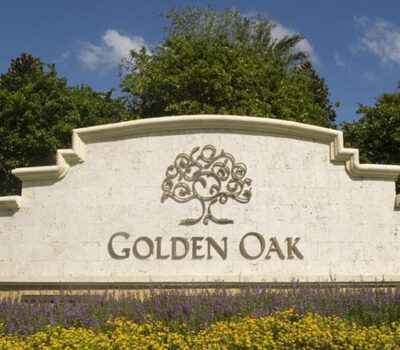 A sign for golden oak is surrounded by flowers and trees