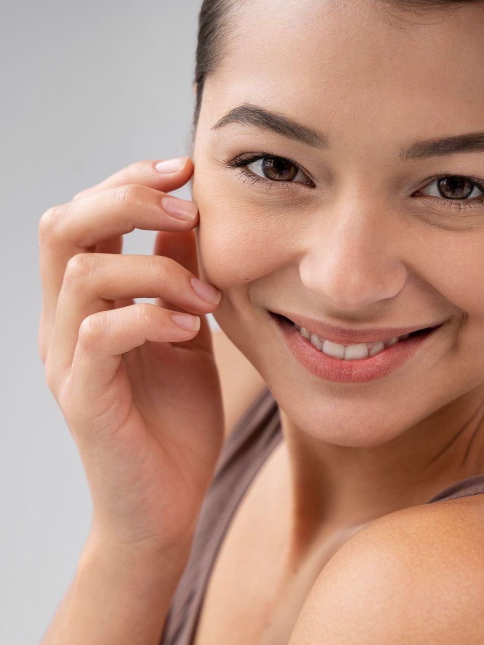 a woman is smiling and touching her face with her hand