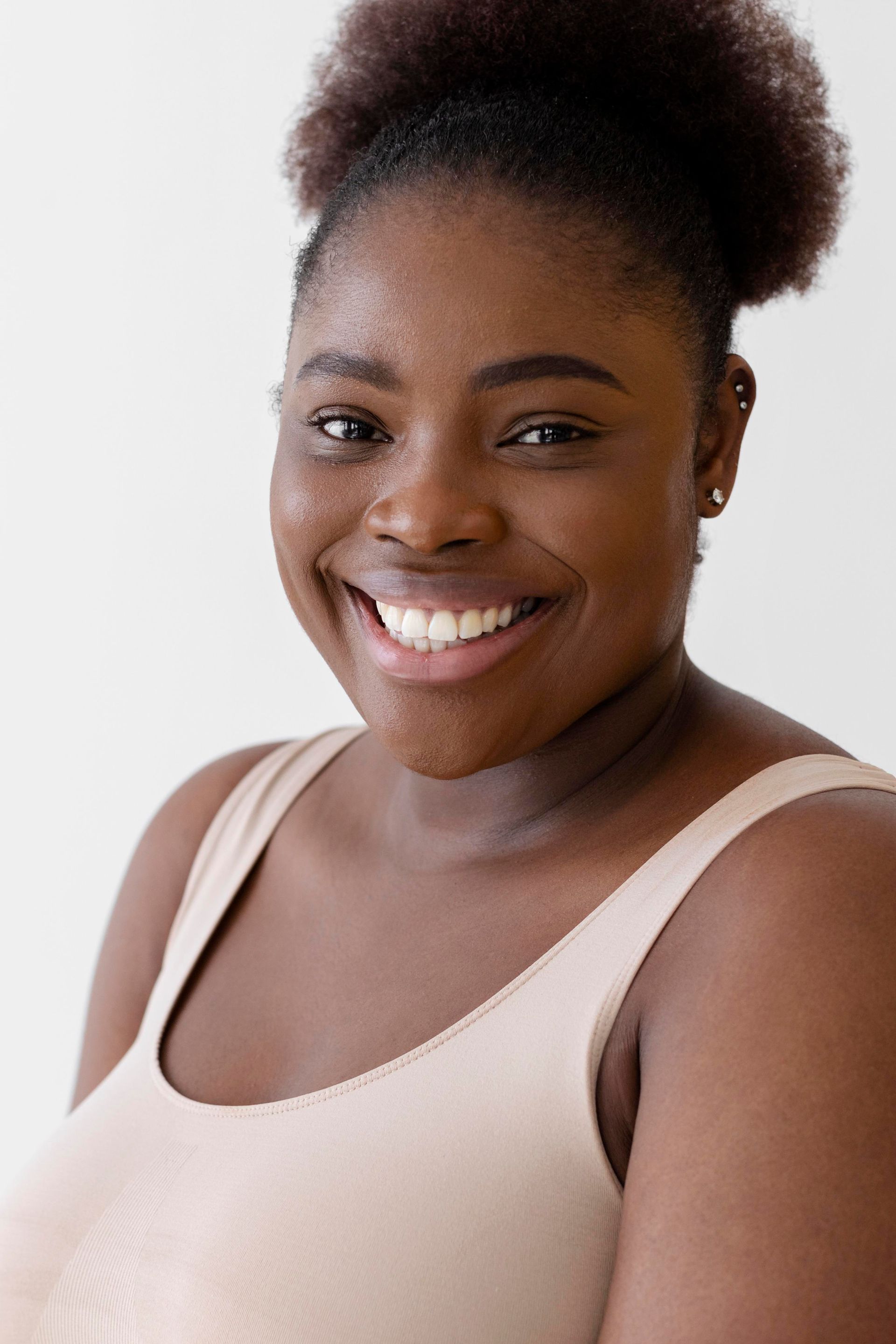 a woman in a tank top is smiling for the camera .