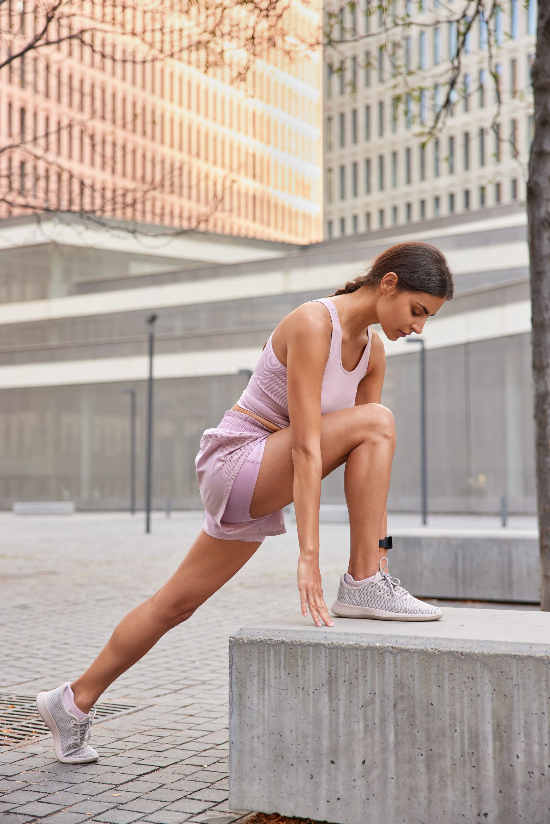 a woman stretches her legs on a concrete block