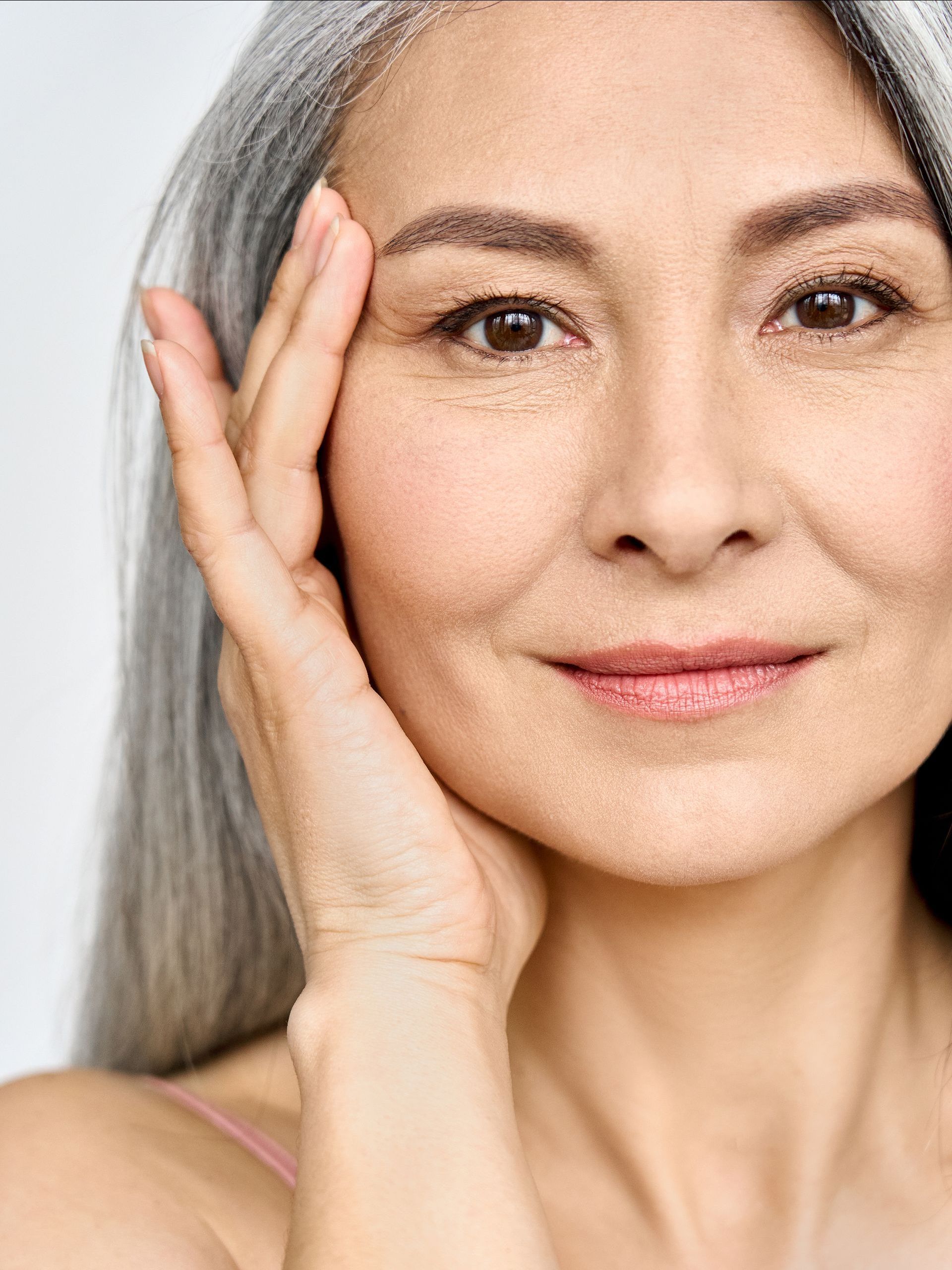 a woman with gray hair touches her face