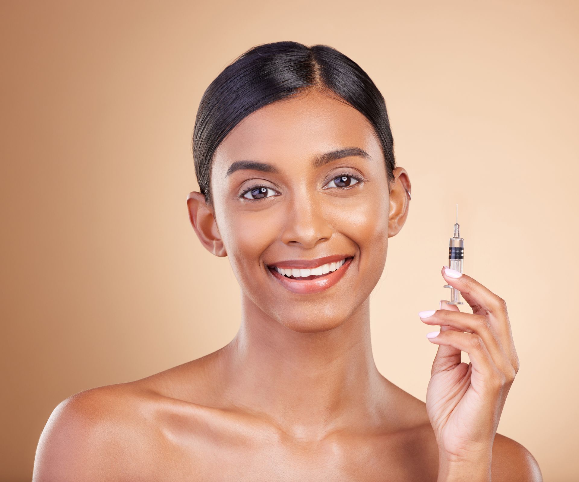 A smiling woman is holding a syringe in her hand.