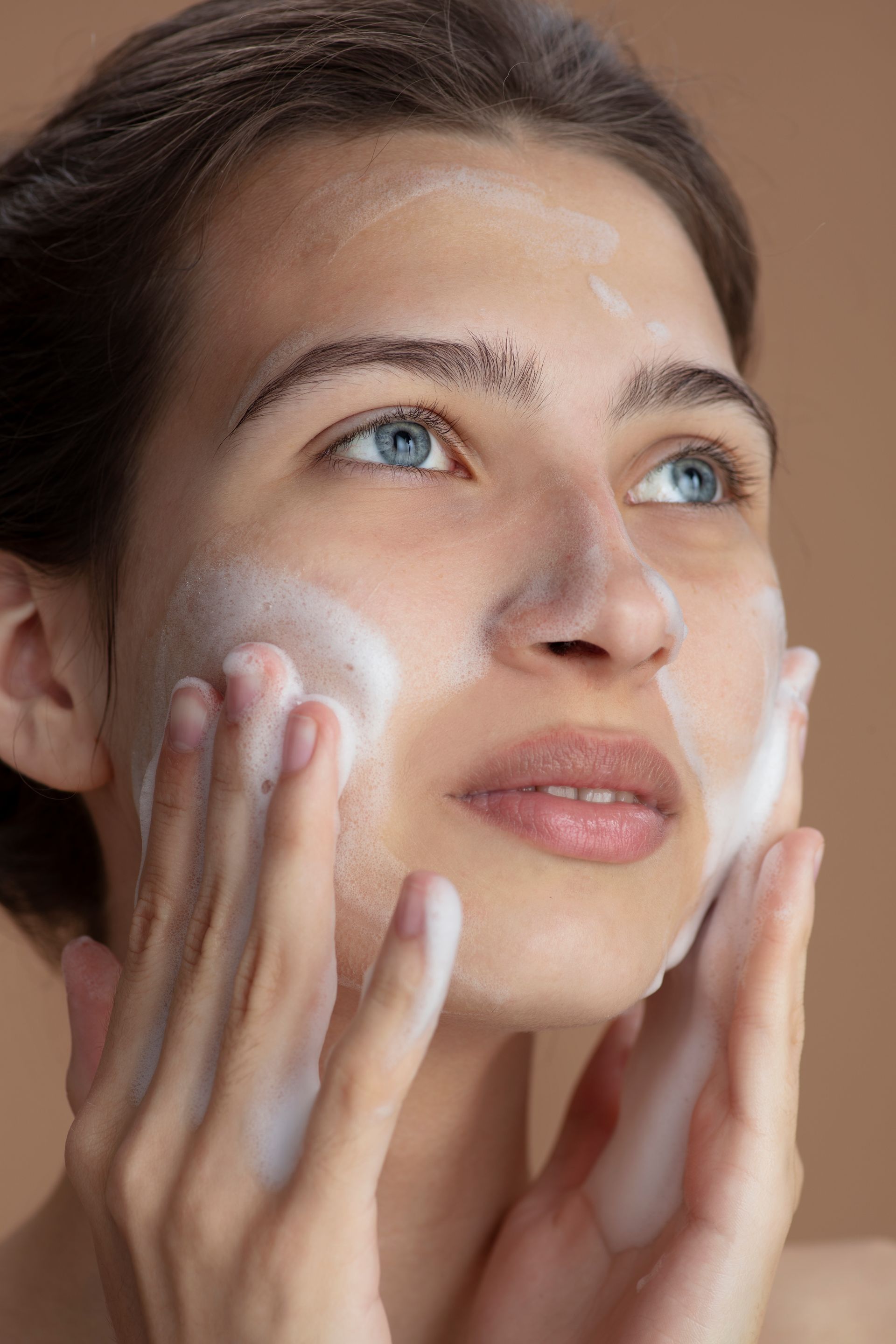 a woman with blue eyes is washing her face with soap