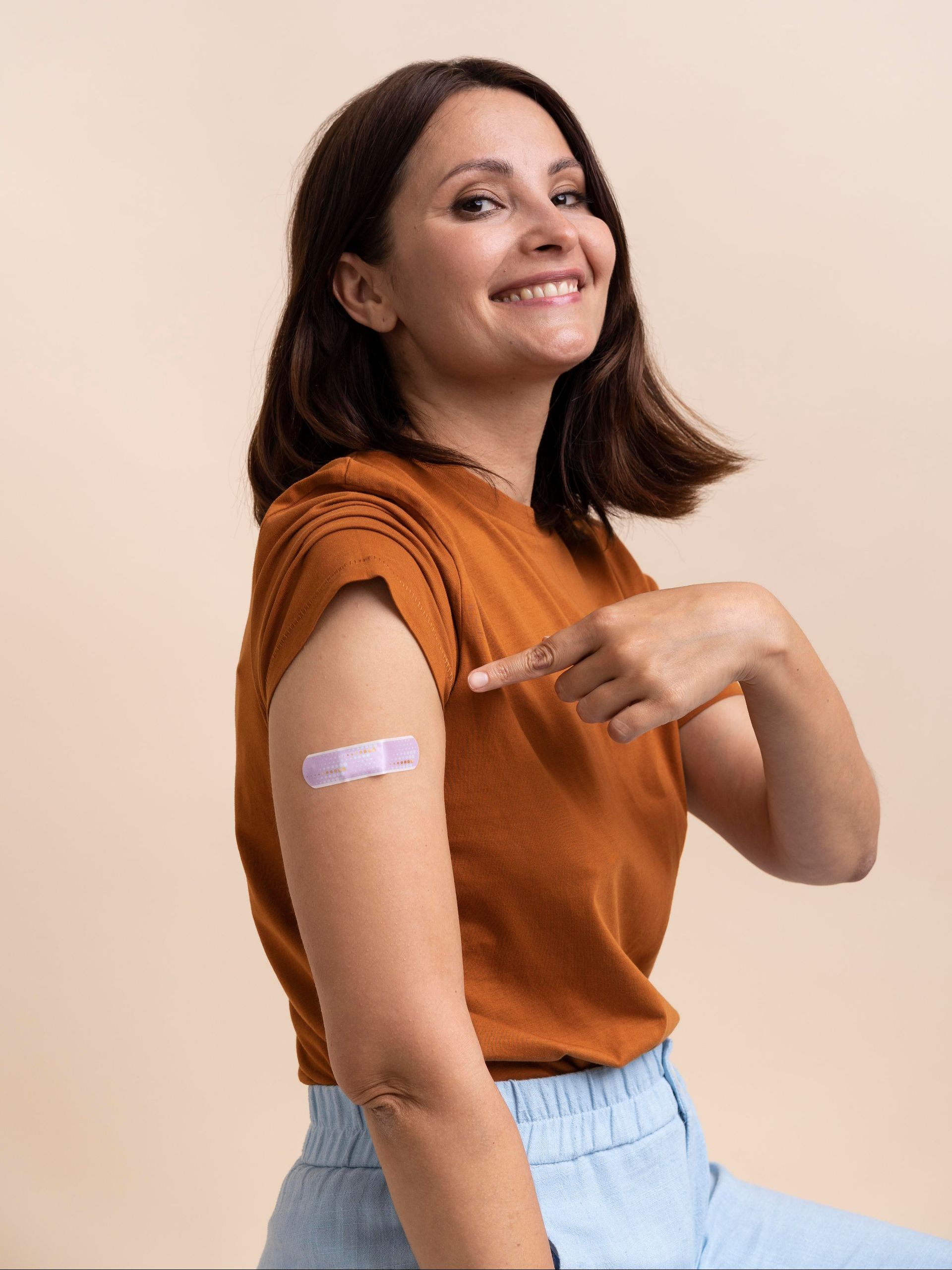 a woman in a brown shirt has a bandage on her arm