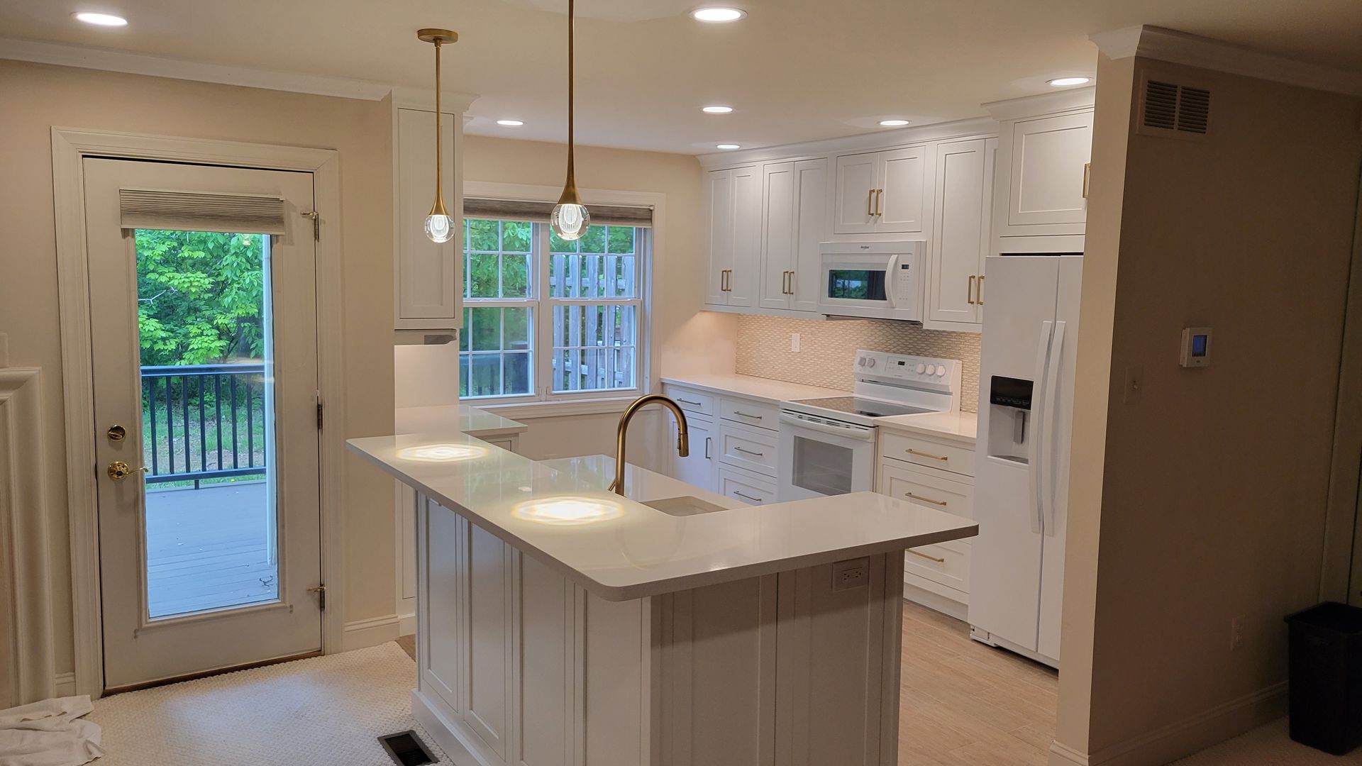 A kitchen with white cabinets , a large island , a refrigerator , and a stove.