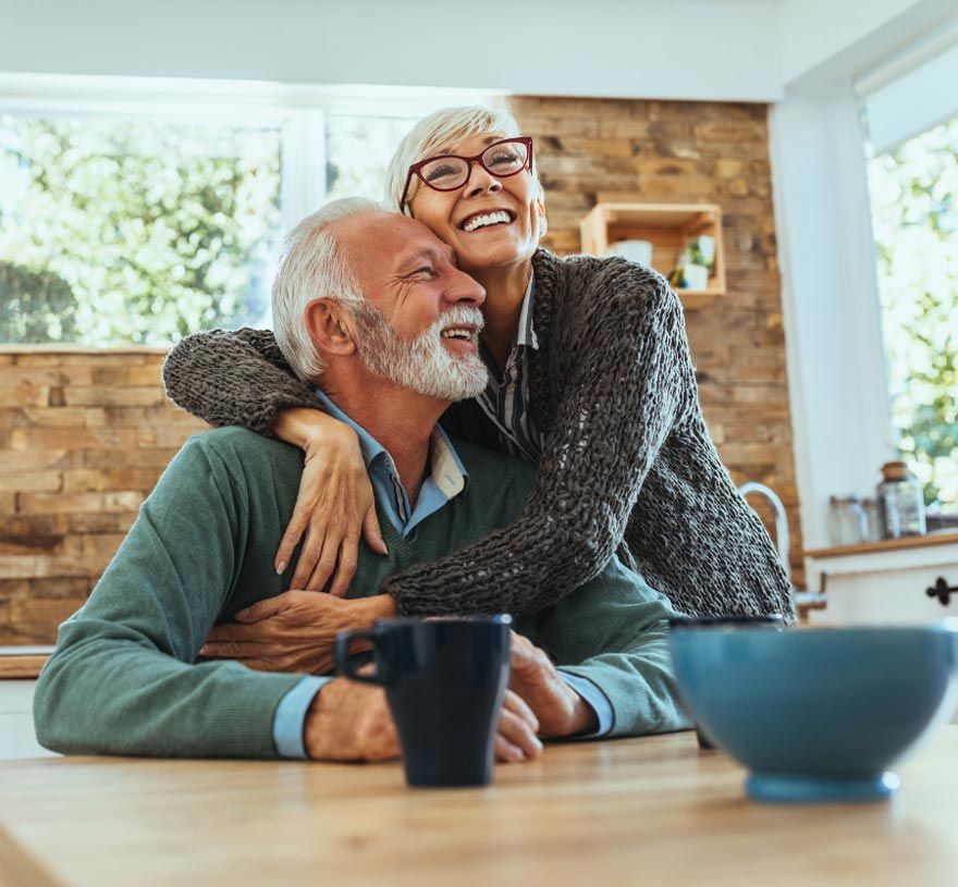 Friendly caregiver sharing a joyful moment with an elderly man, promoting companionship and emotional well-being.
