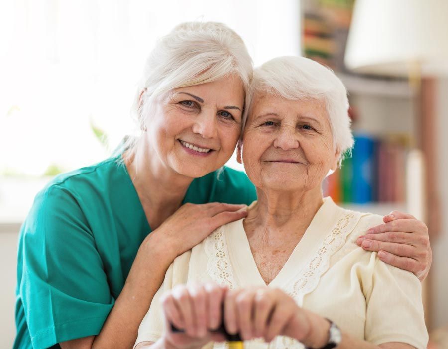 Happy senior woman embracing a compassionate caregiver, receiving personalized in-home care.