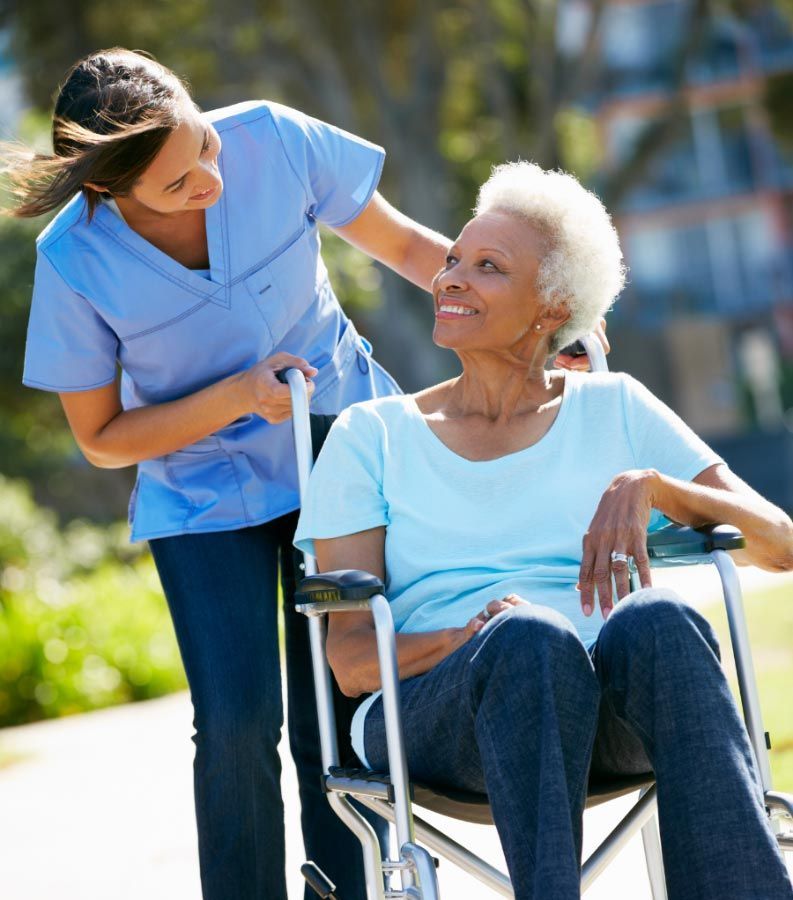 Senior woman enjoying the outdoors with a caregiver, promoting mobility and well-being.