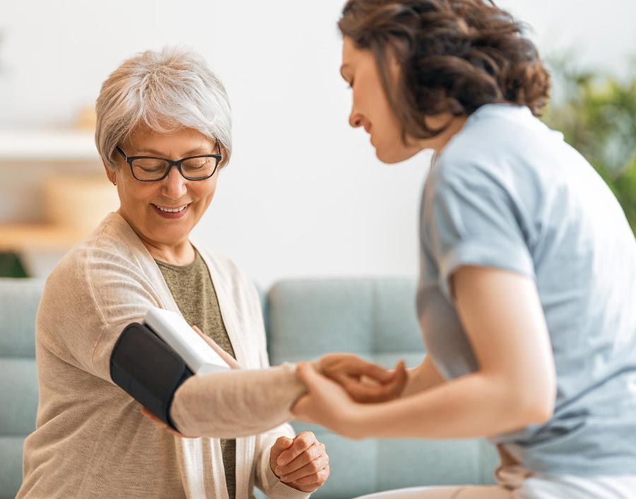Professional caregiver assisting a senior with health monitoring and personalized in-home care services.