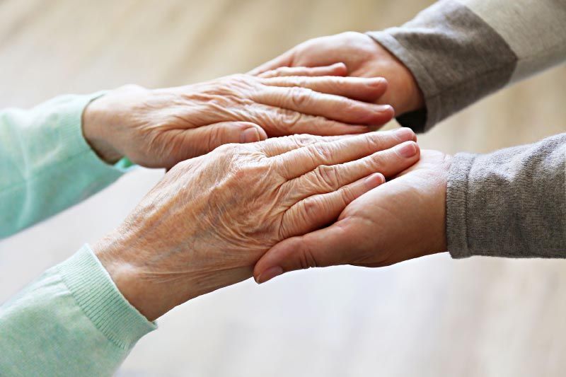 Close-up of caregiver holding elderly hands, symbolizing compassion, trust, and dedicated home care services.