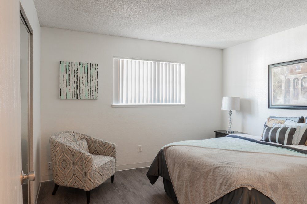A bedroom with a bed , chair and window.