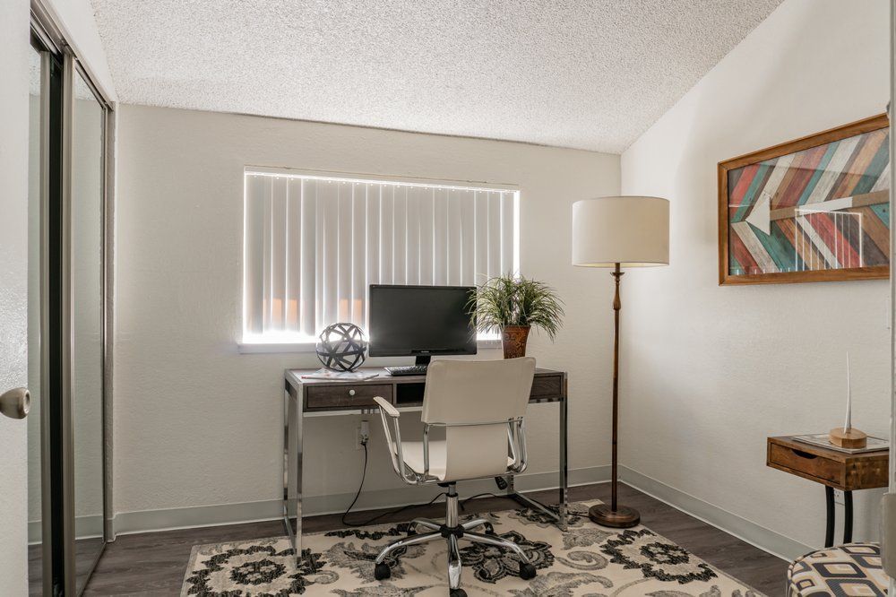A home office with a desk , chair , lamp and computer.